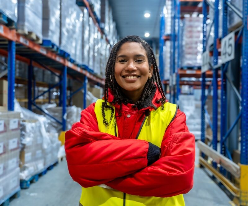 Smiling,Young,Woman,Standing,With,Arms,Crossed,In,A,Brightly